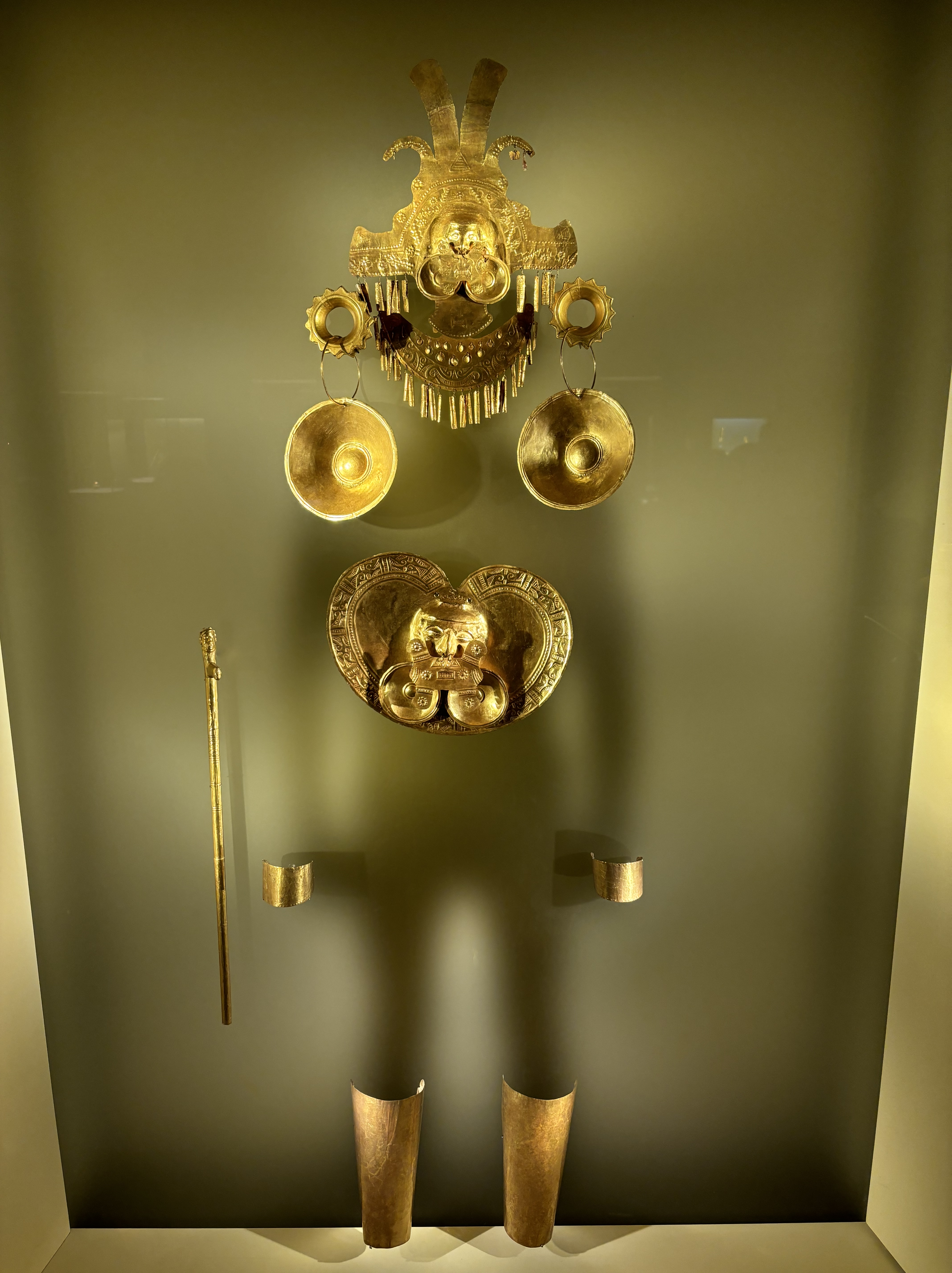 Silhouette of a man adorned with intricate gold headdress and chest plate and other ancient accessories.