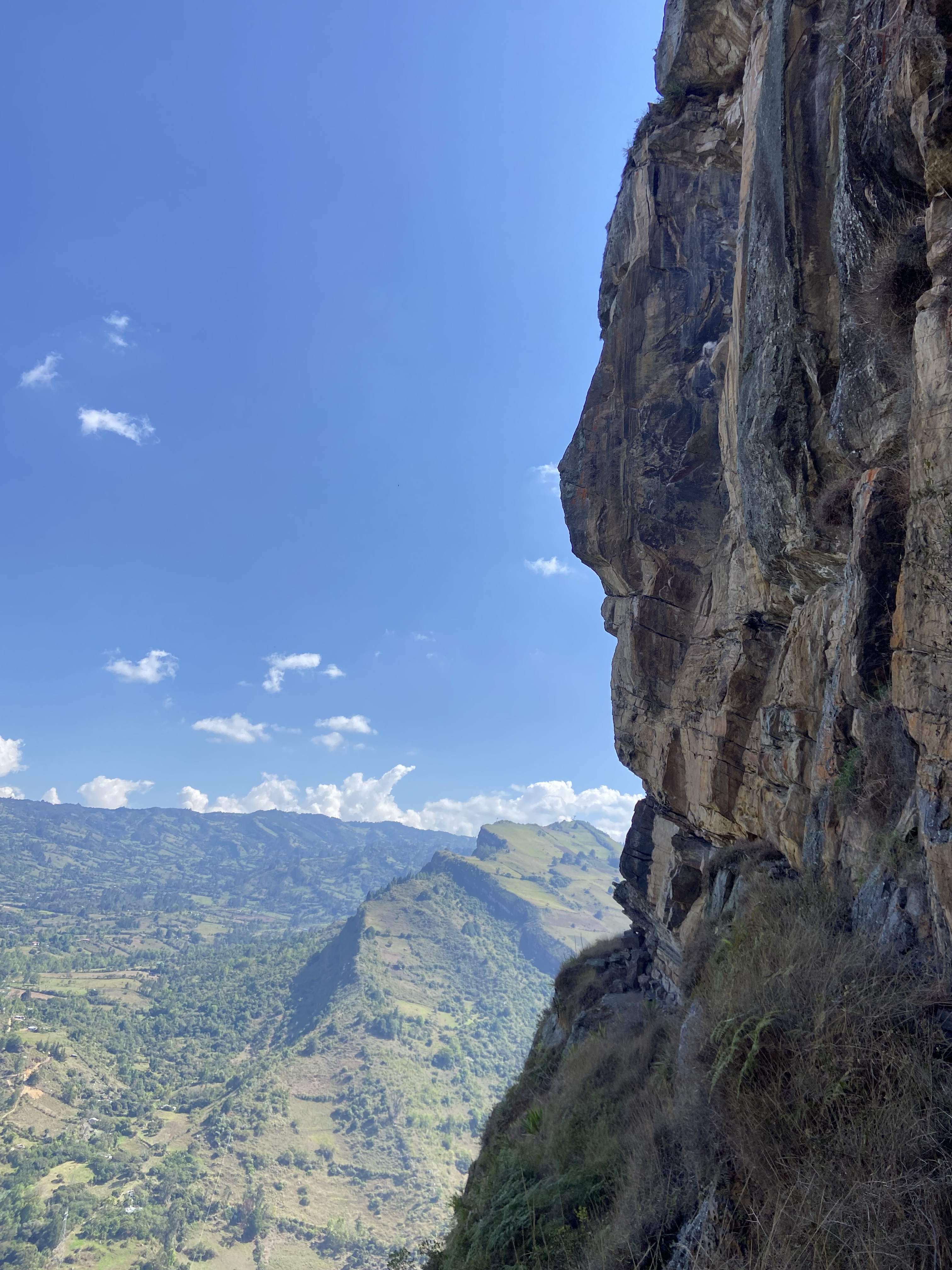 Sandstone crag perched on a ledge looking out over the green valley below.