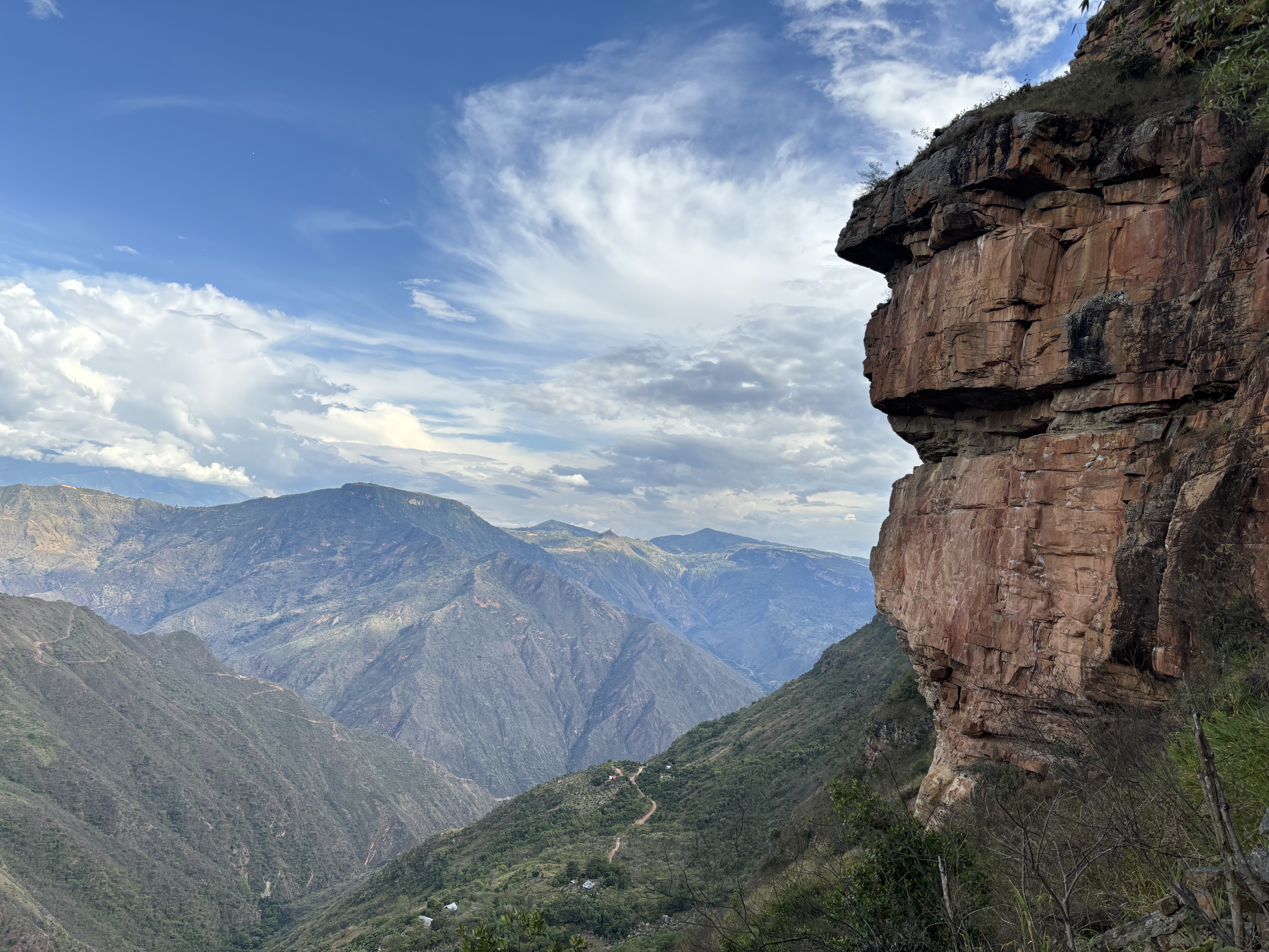 Orange band of sandstone cliffs perched high on the mountain side set within a steep sided canyon.