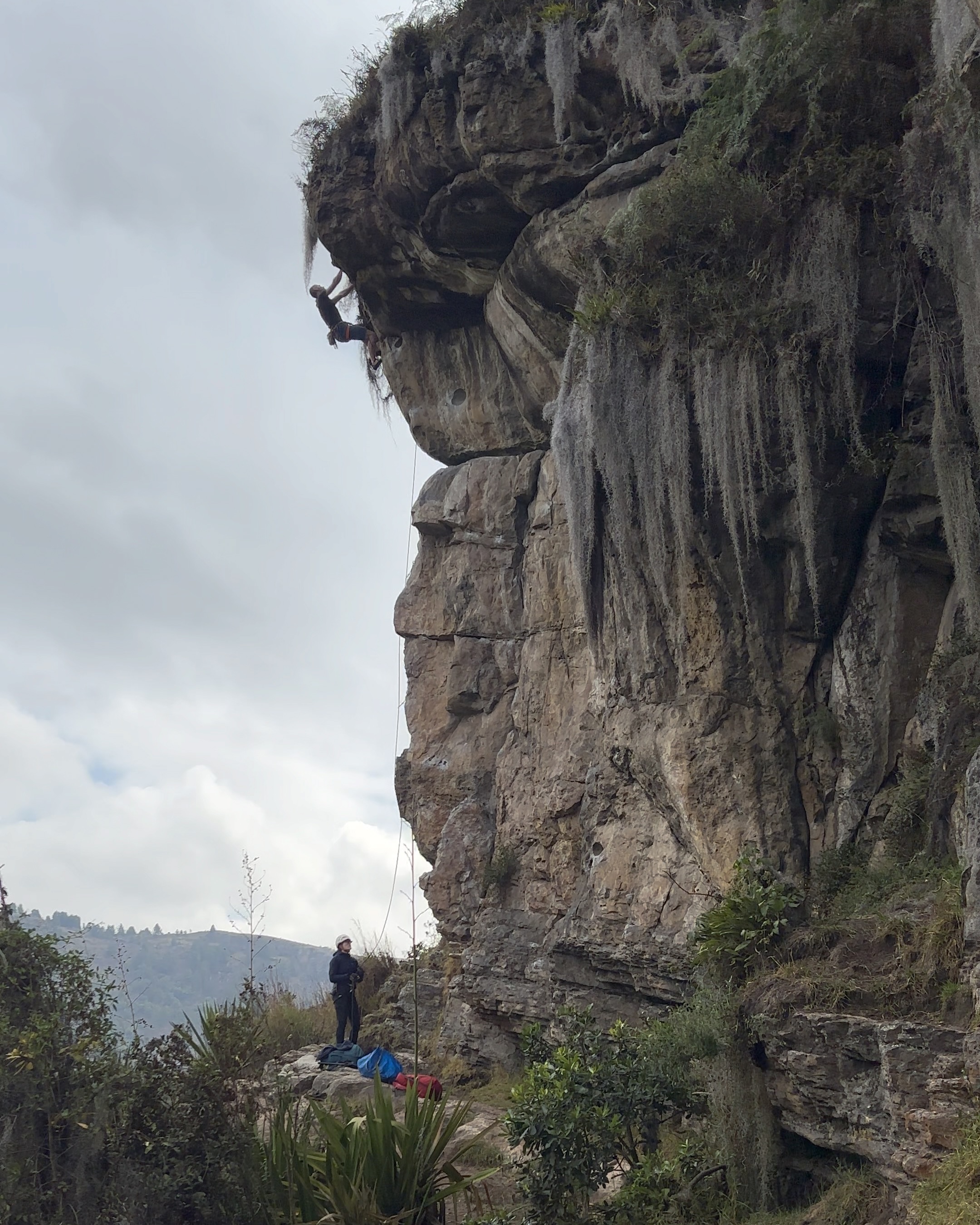 Climber on the steep finish to a climb on a sandstone buttress which features large huecos and horizontal breaks. 