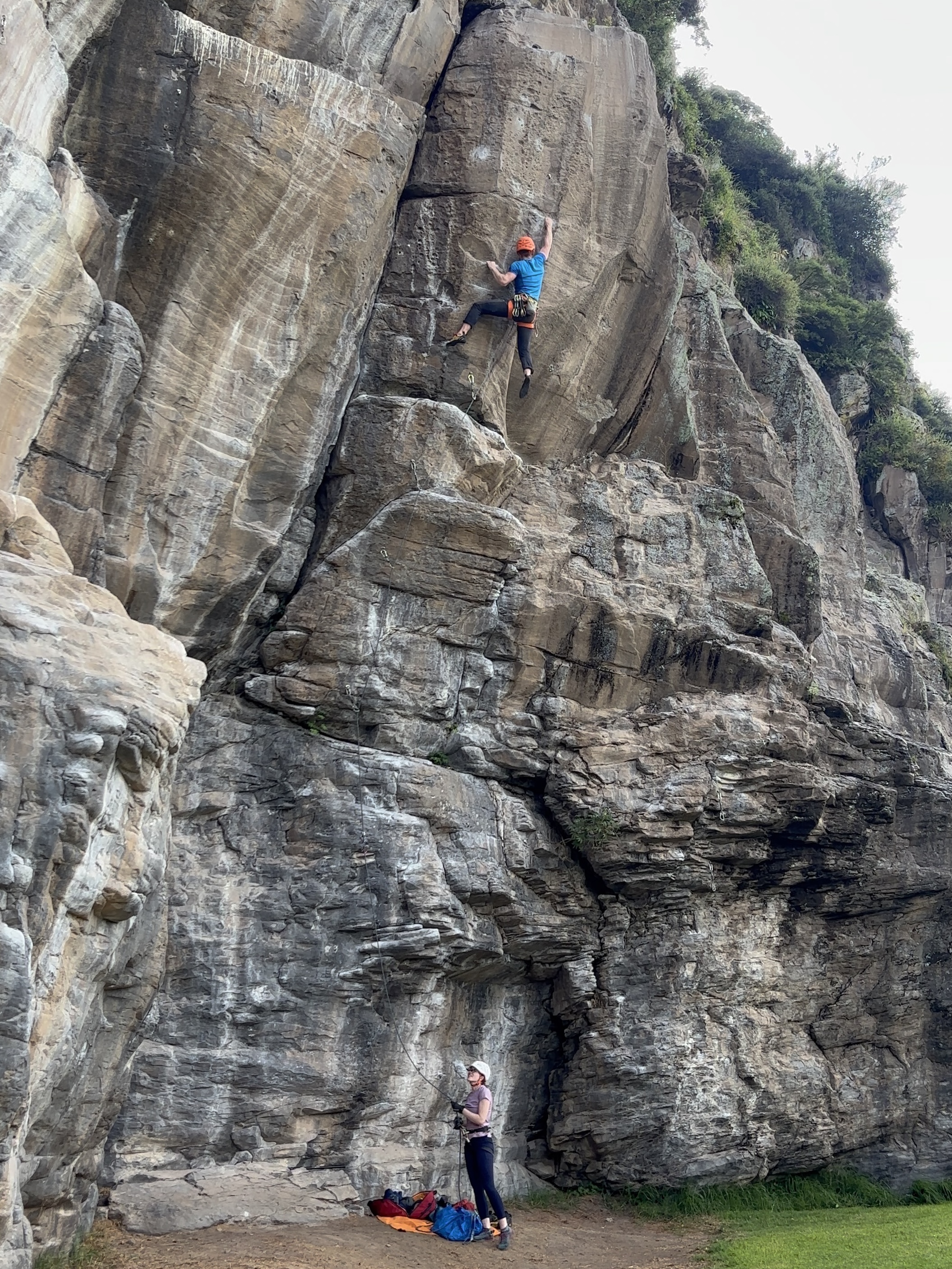 Climber moving dynamically on a steep volcanic rock wall.