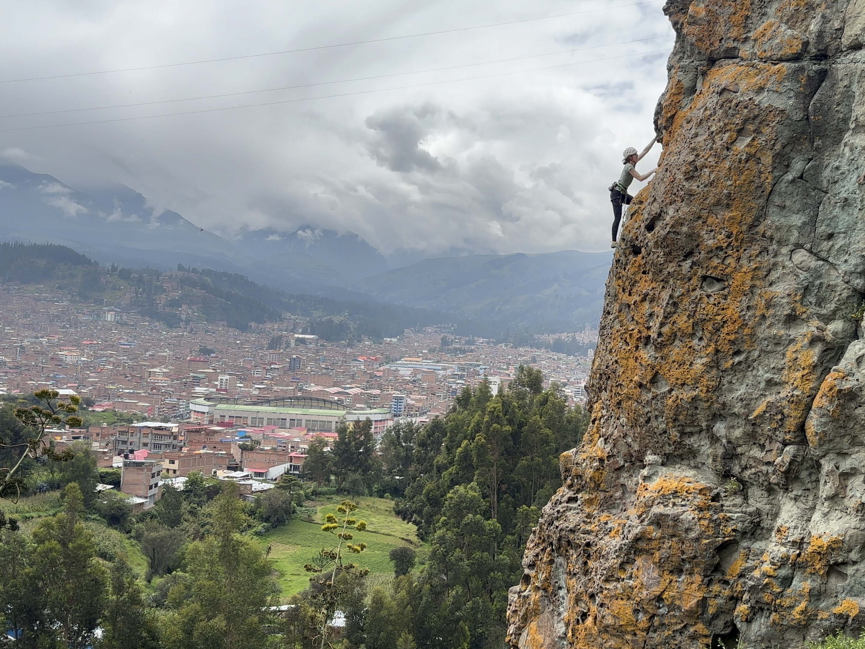 Climber on an arête above a sprawling city in the background. 