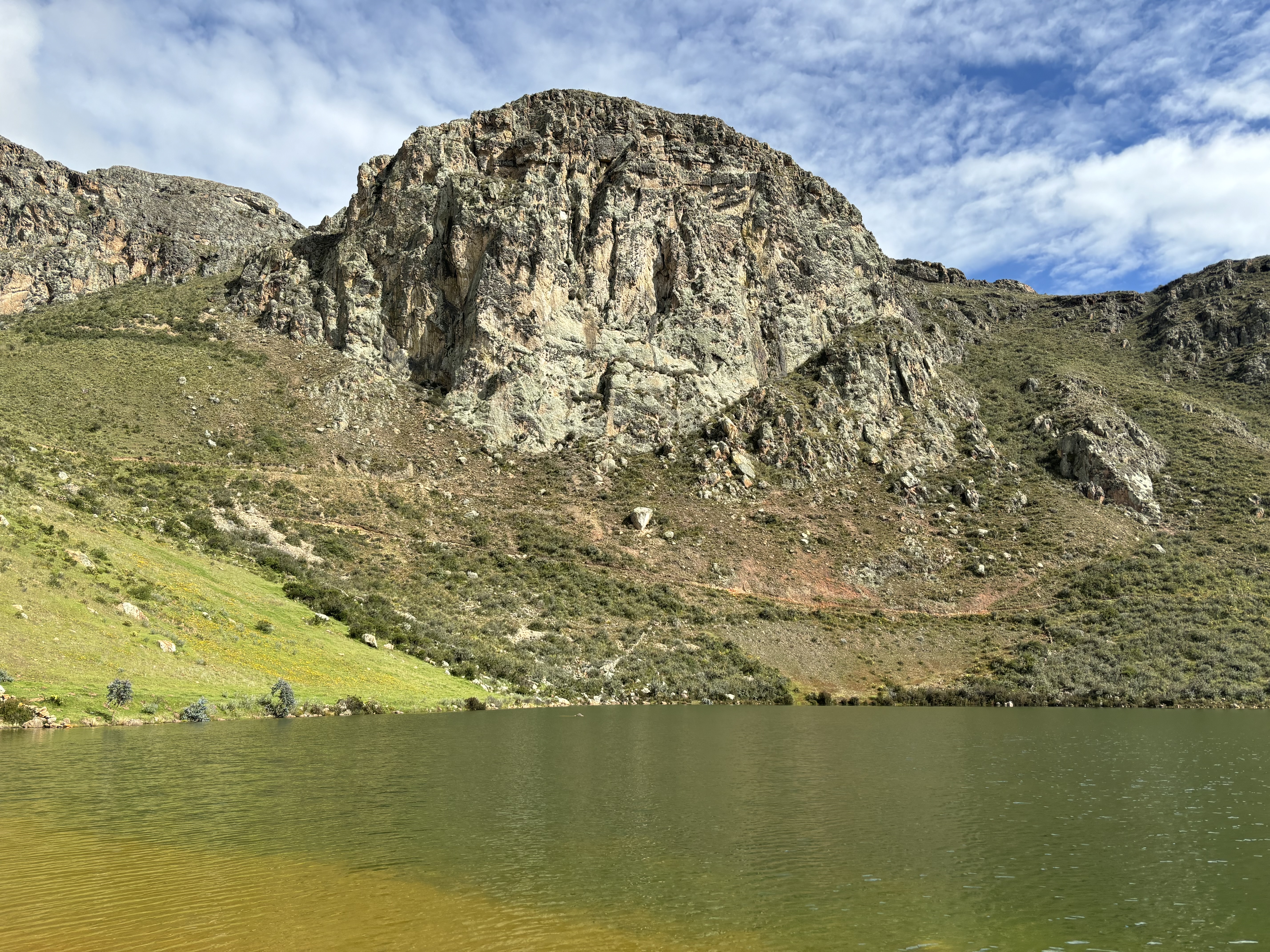 Large limestone buttress set upon a steep hillside above a large green lake.  