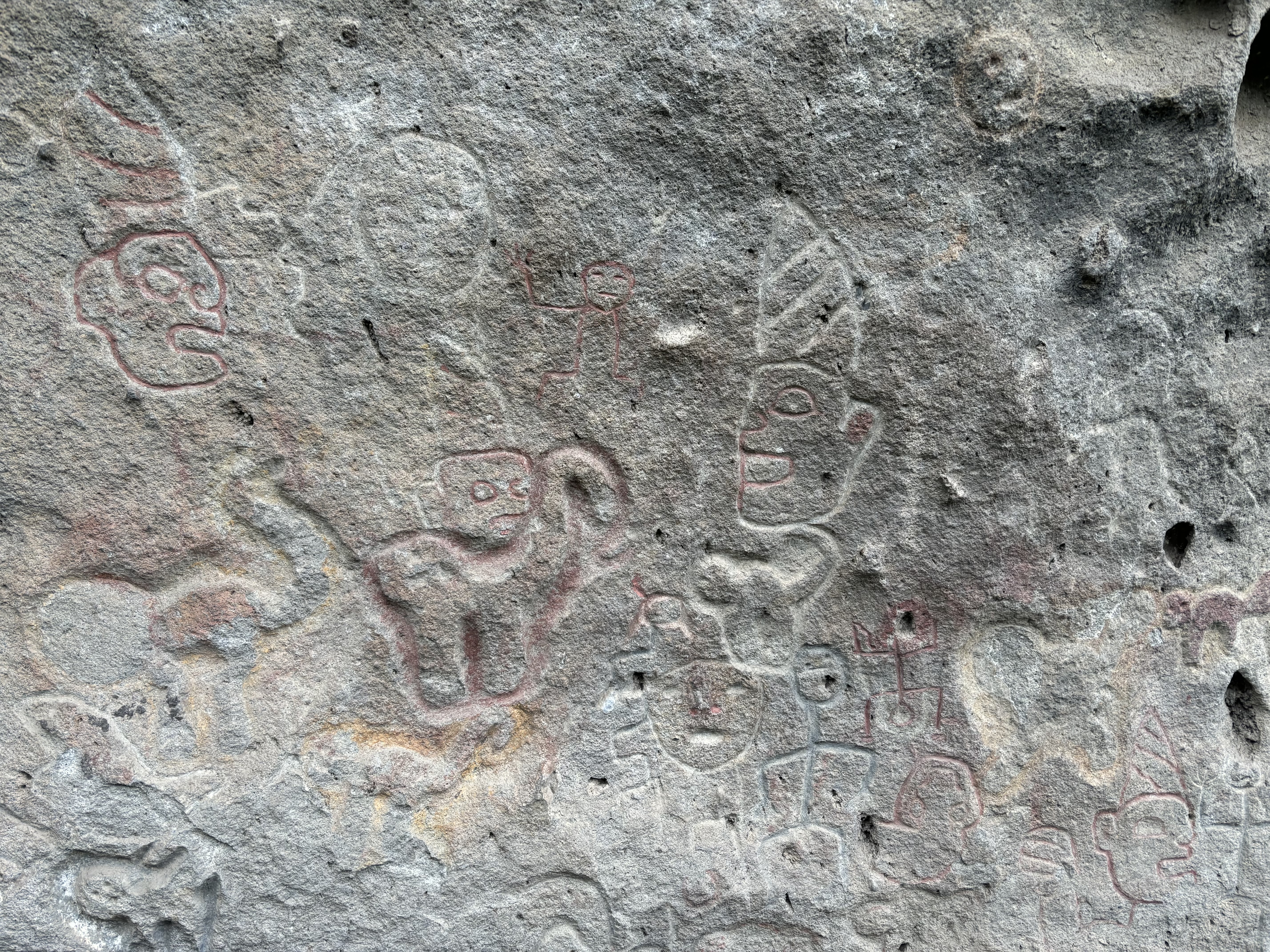 Ancient stone carvings which feature mystical people with fragments of red paint remaining. 