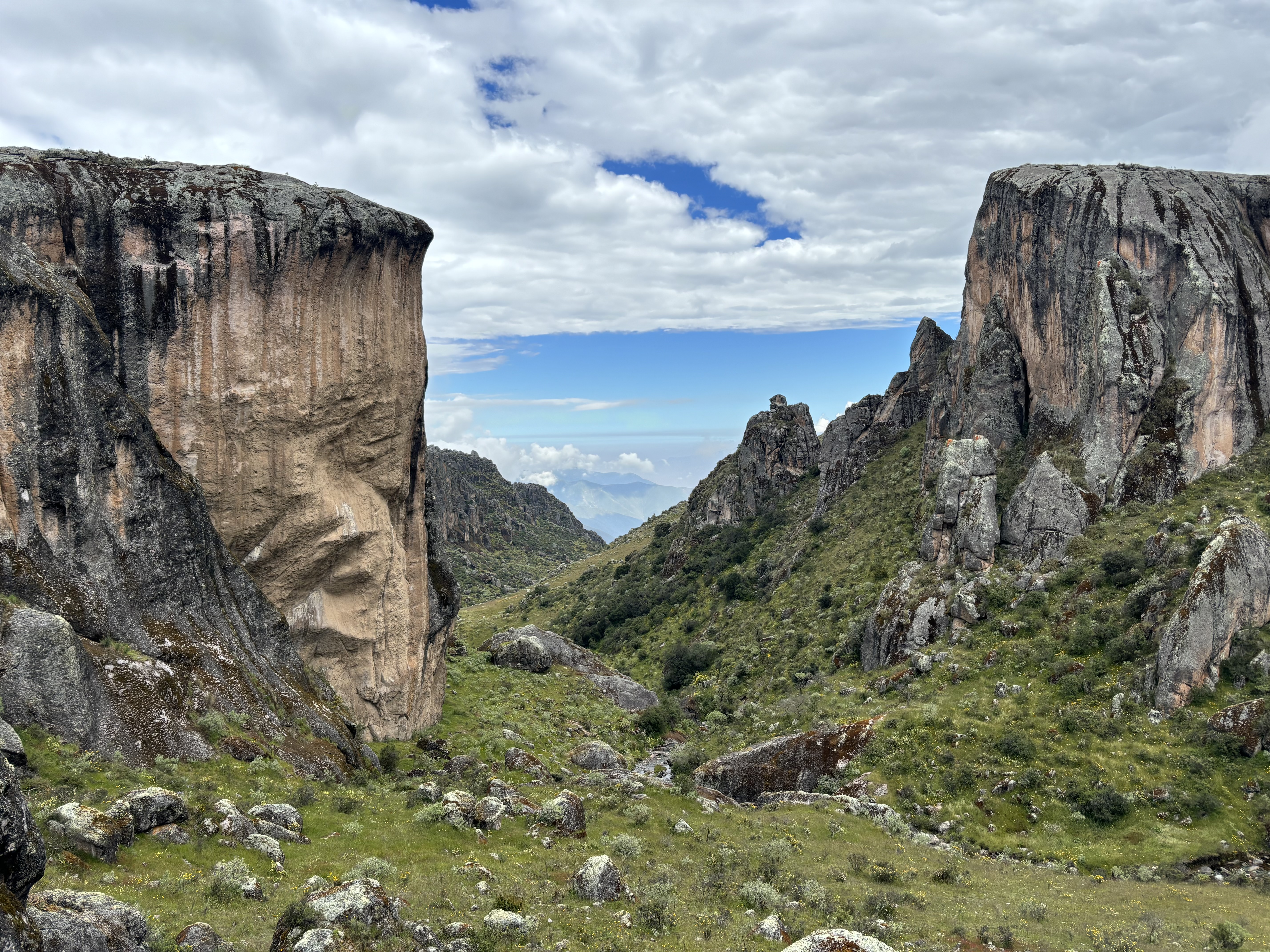 Tall volcanic rock cliffs line both sides of a serene and remote valley. 