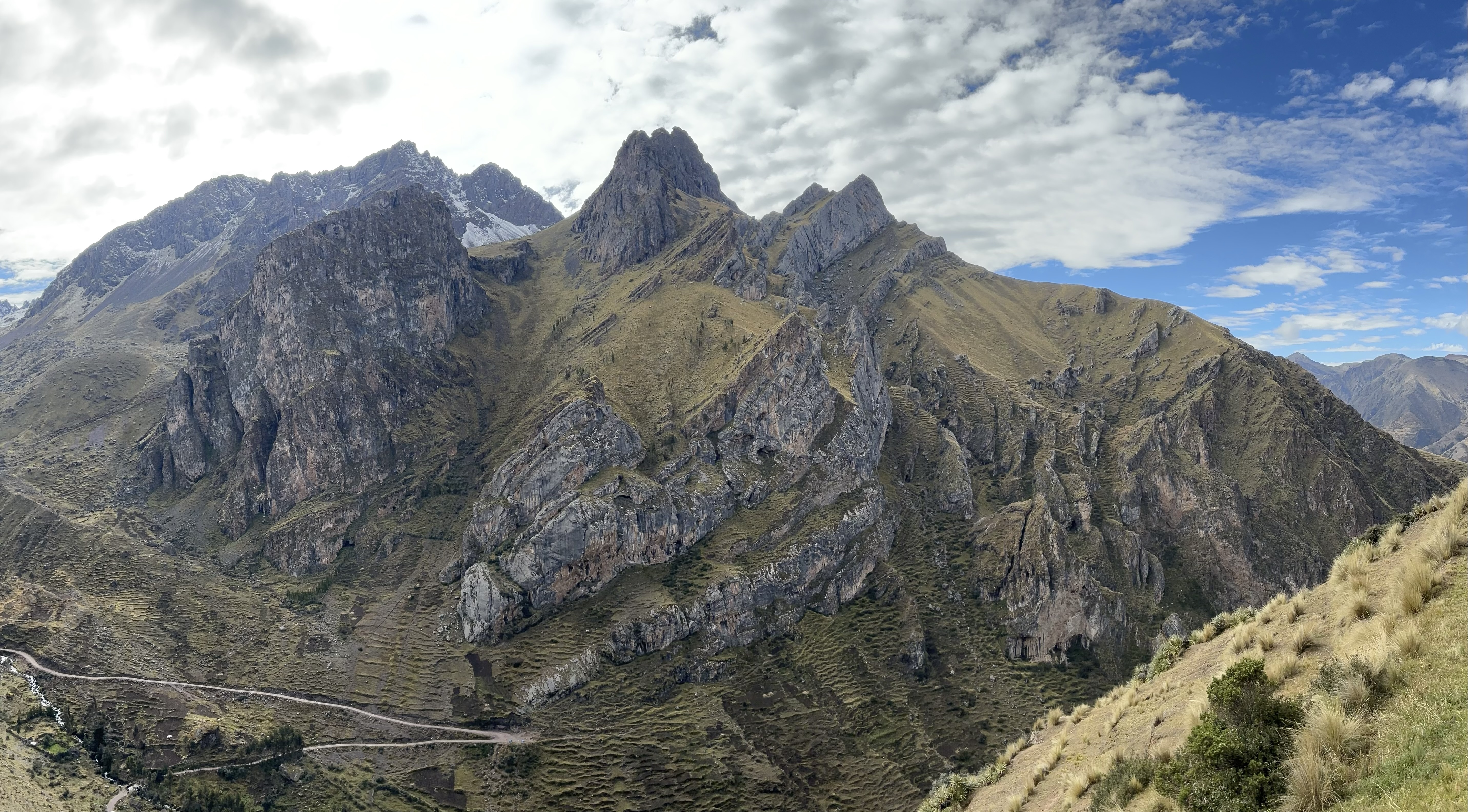 Deep valley covered in fins of limestone rock. A steep road cuts across the valley side, with terraced fields visible high on the mountain side. 
