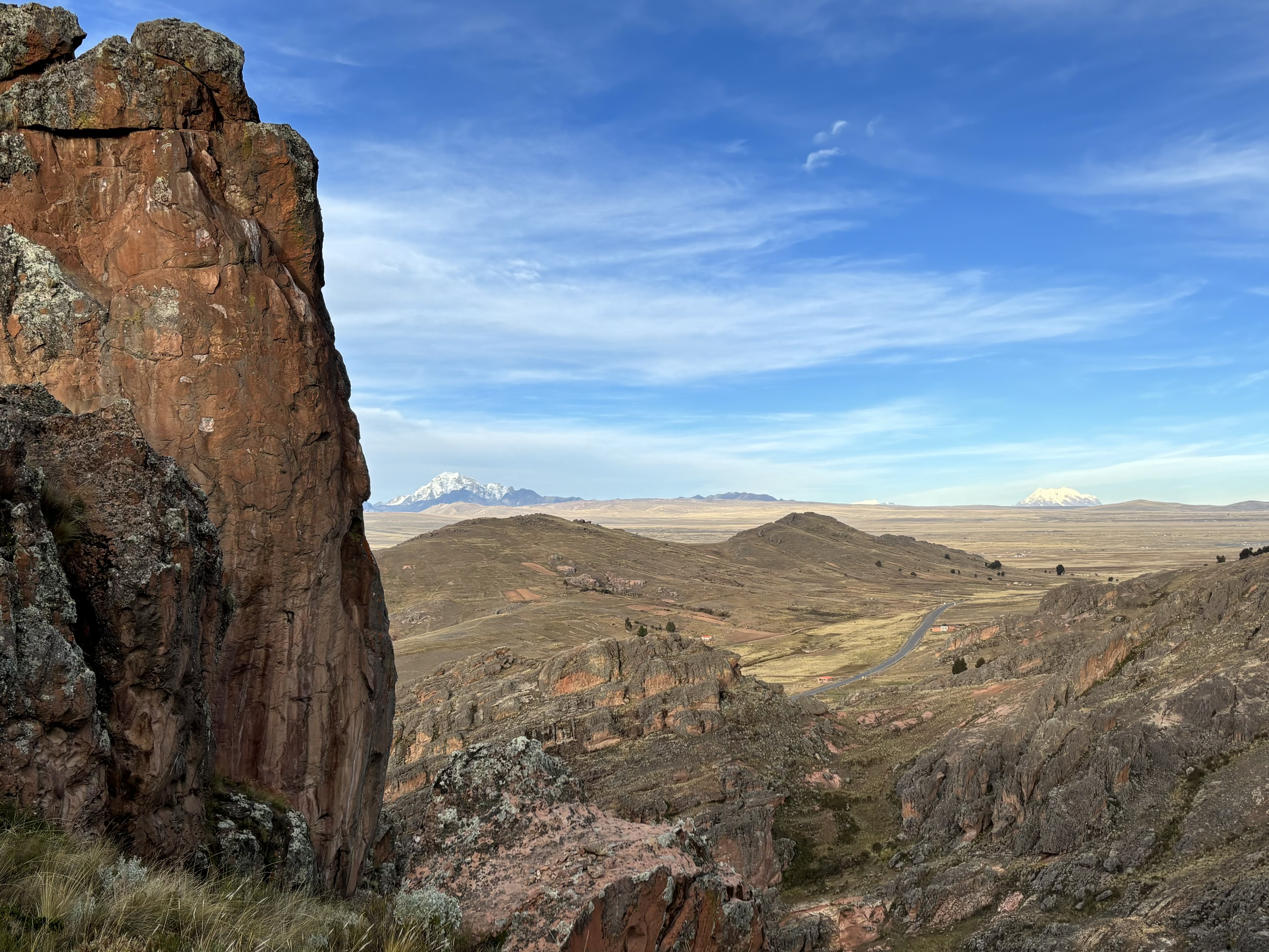 Orange sandstone sectors of rock on the hillside with a snowy mountain range in the background.