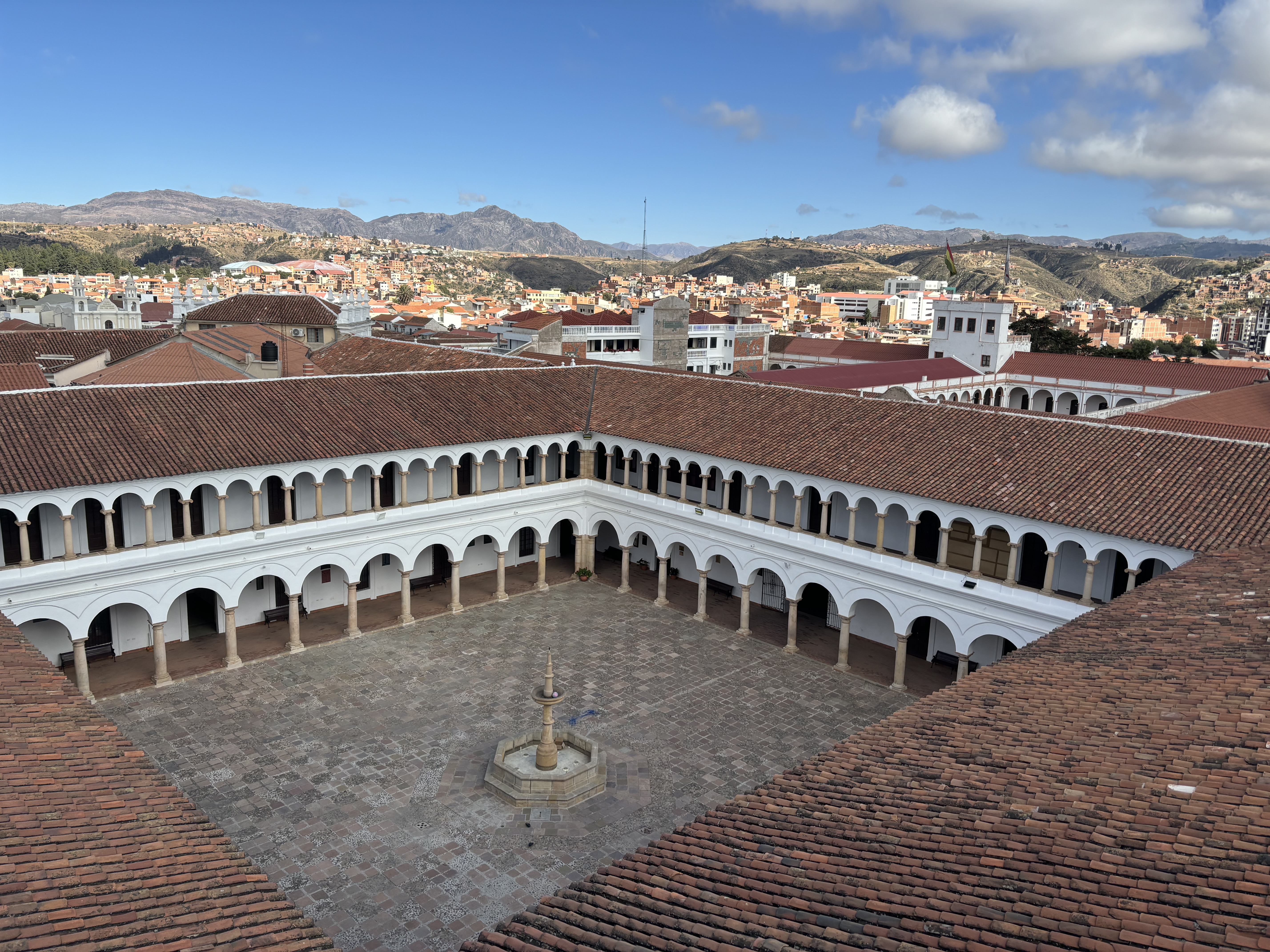 Large white courtyard filled with archways and with a central fountain.