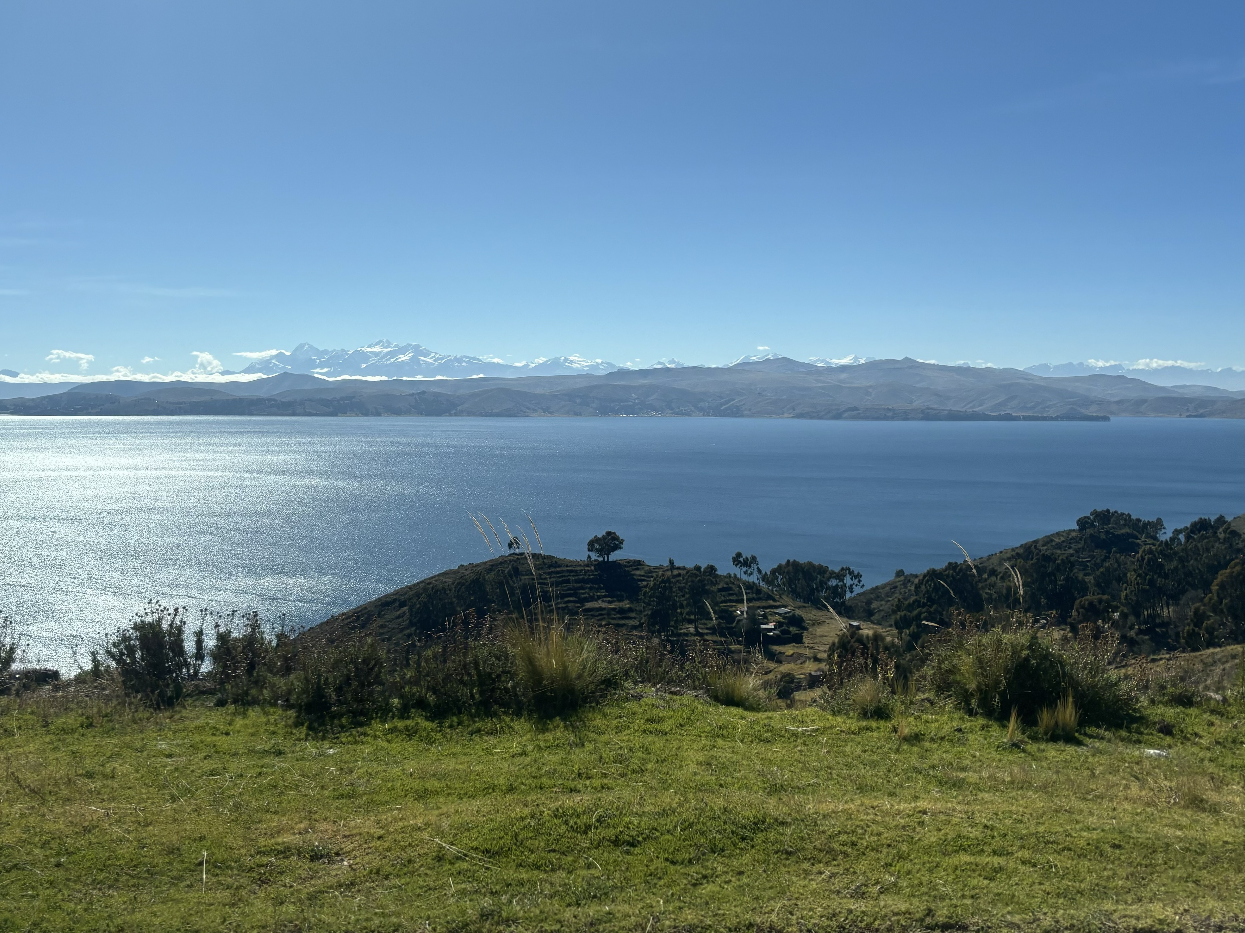 Blue lake with snowy, high altitude mountain range in the background.