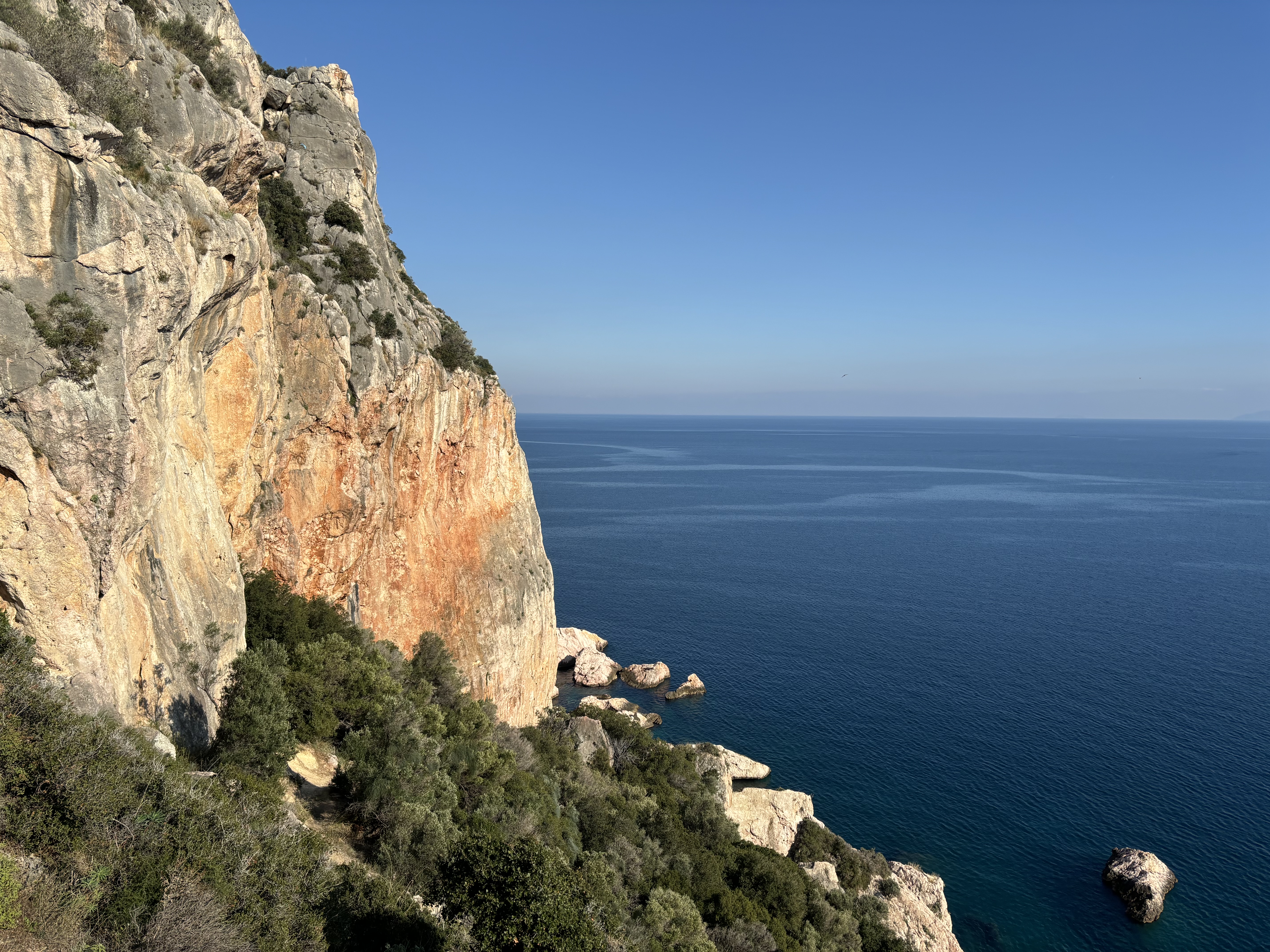 Large orange and grey limestone buttress by the above the sea.