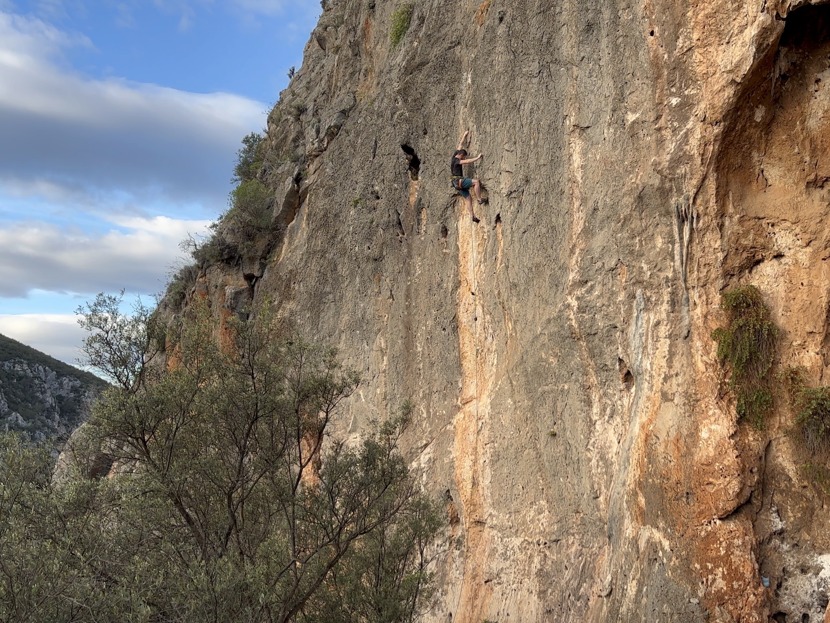 Climber using a high foot to pass an overlap on a thin grey vertical wall climb.