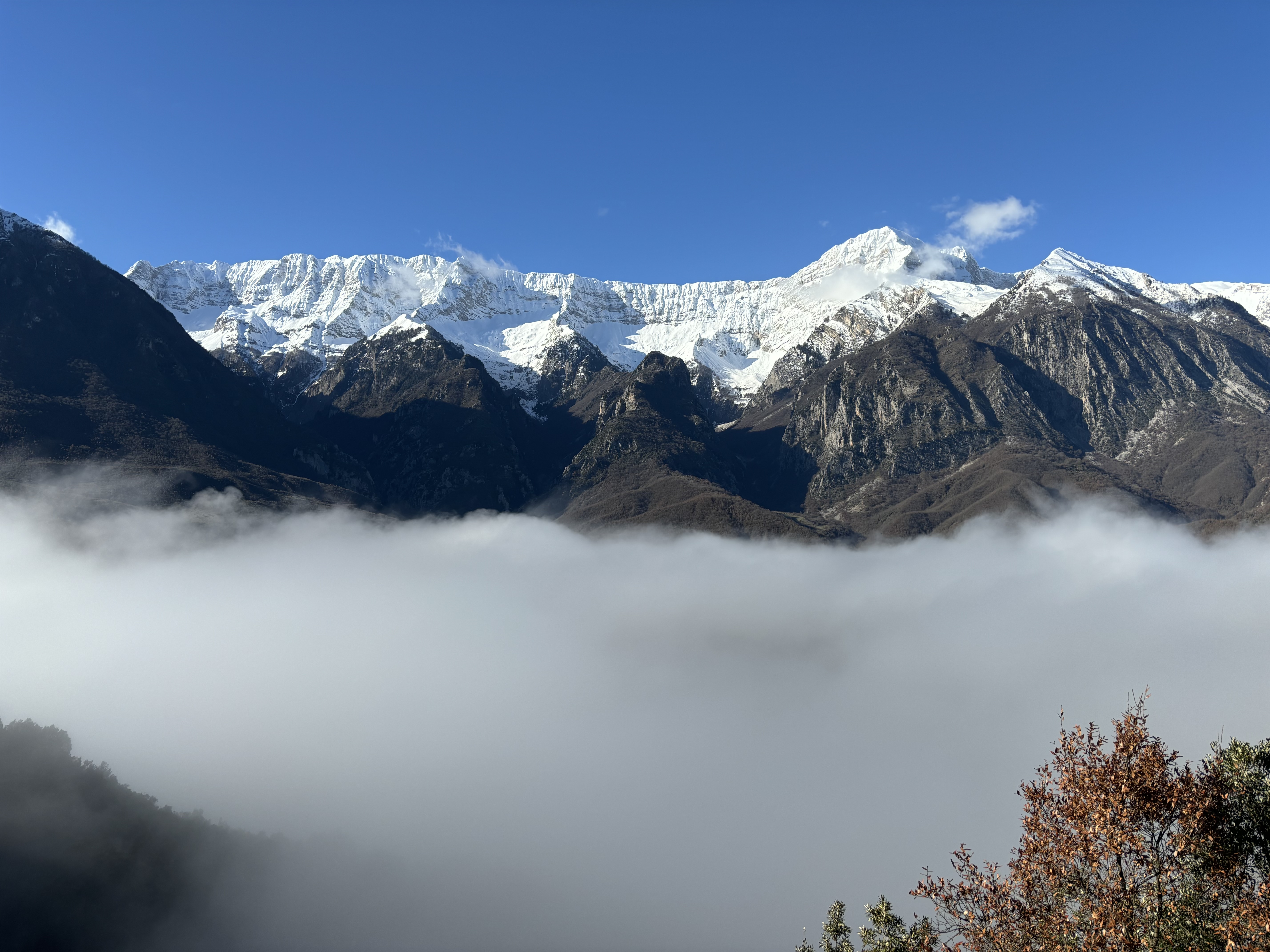 Big, snowy mountains rise above a cloud inversion. 