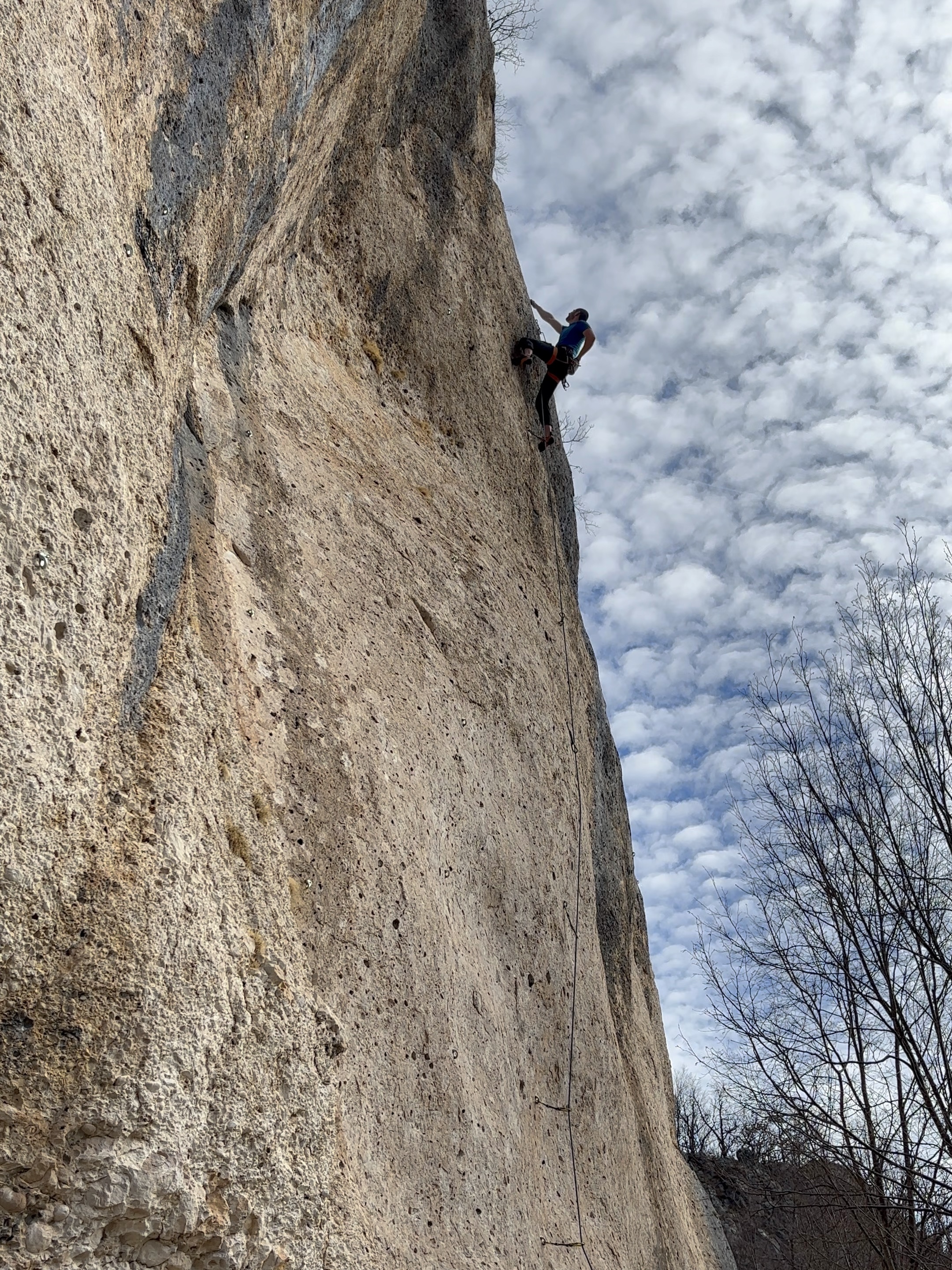 A climber chalks up before tackling the crux of a beautiful pocketed conglomerate limestone cliff that is almost bone white in colour. 